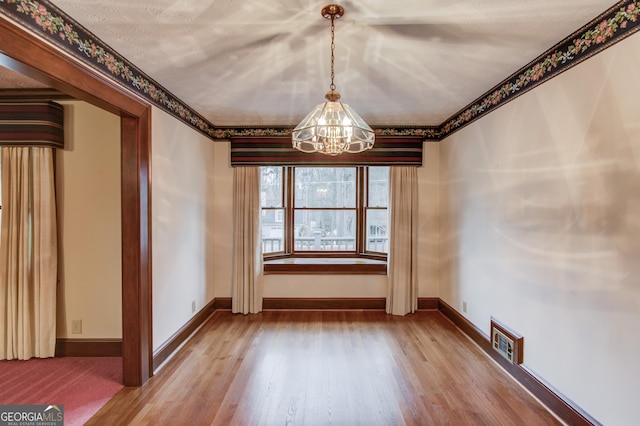 unfurnished dining area featuring hardwood / wood-style floors and a chandelier