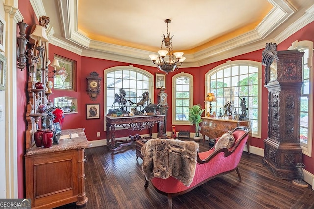 sitting room with ornamental molding, dark wood-type flooring, a notable chandelier, and a tray ceiling