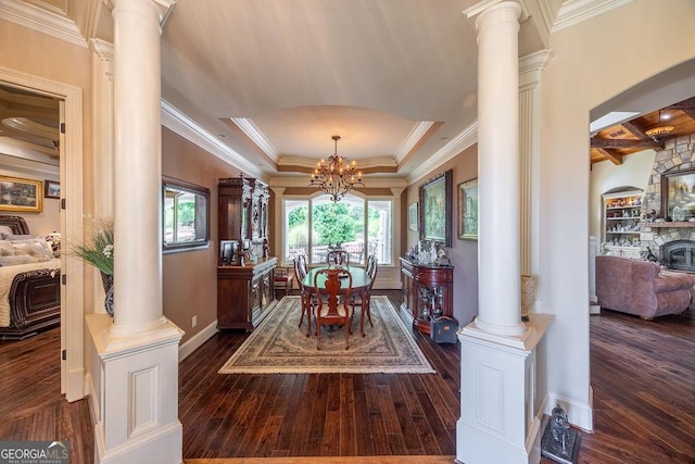 dining area featuring ornate columns, crown molding, a chandelier, a tray ceiling, and dark hardwood / wood-style flooring