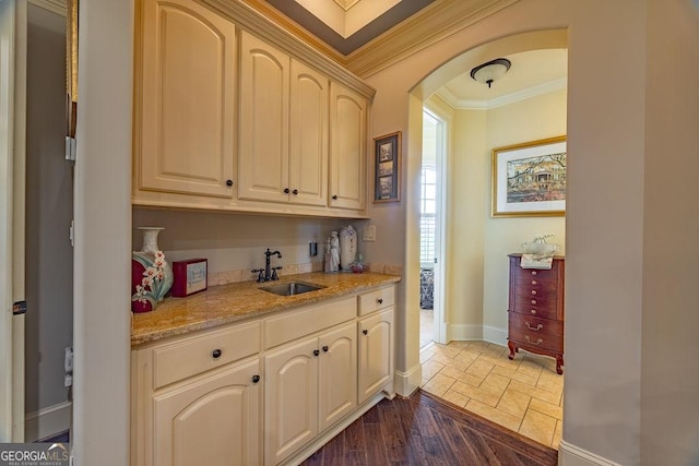 bar with ornamental molding, light stone countertops, sink, and dark wood-type flooring