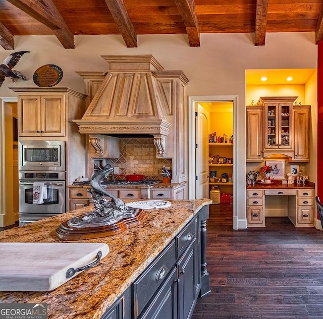 kitchen featuring built in desk, appliances with stainless steel finishes, dark hardwood / wood-style floors, custom range hood, and light stone countertops