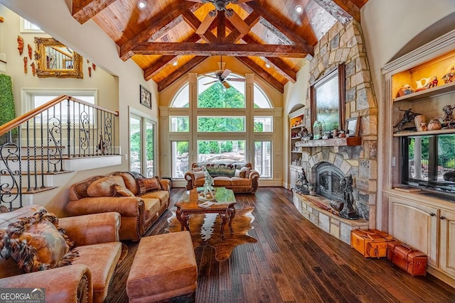 living room featuring a stone fireplace, high vaulted ceiling, dark hardwood / wood-style floors, ceiling fan, and beam ceiling