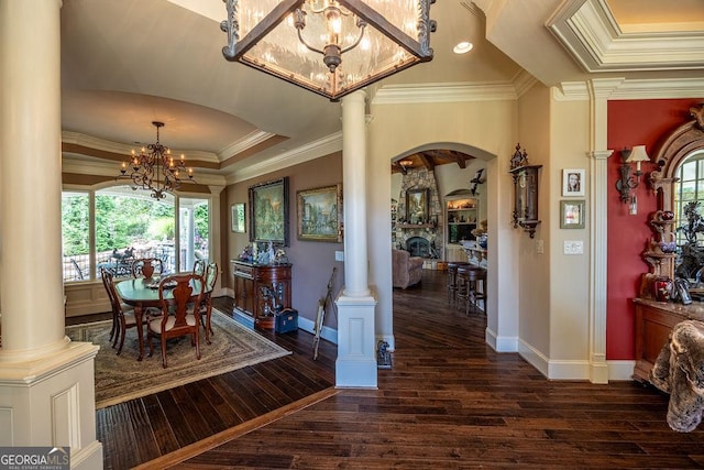 dining space with ornate columns, an inviting chandelier, ornamental molding, dark hardwood / wood-style flooring, and a tray ceiling