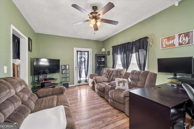 living room with a textured ceiling, wood-type flooring, and ceiling fan