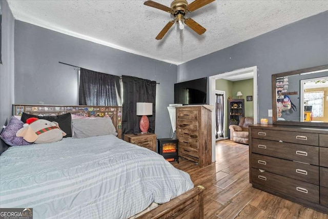 bedroom with ceiling fan, hardwood / wood-style flooring, and a textured ceiling