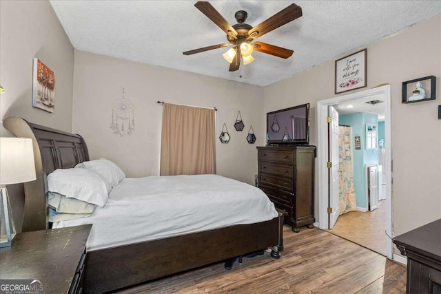 bedroom featuring ceiling fan, hardwood / wood-style floors, and a textured ceiling