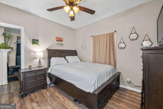 bedroom featuring ceiling fan, dark wood-type flooring, and a textured ceiling