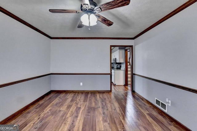 spare room with a textured ceiling, dark wood-type flooring, ornamental molding, and ceiling fan