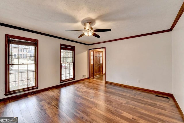 spare room featuring dark wood-type flooring, ceiling fan, crown molding, and a textured ceiling