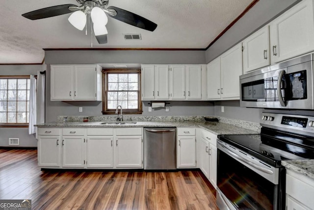 kitchen featuring white cabinetry, sink, light stone countertops, and appliances with stainless steel finishes