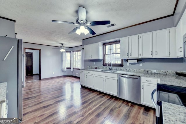 kitchen with sink, dark wood-type flooring, appliances with stainless steel finishes, white cabinetry, and light stone counters