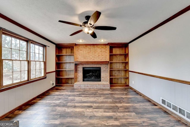 unfurnished living room with dark hardwood / wood-style flooring, a brick fireplace, crown molding, and a textured ceiling