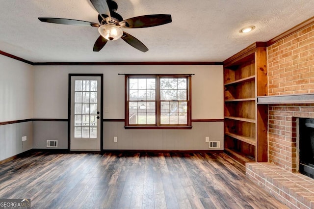 unfurnished living room featuring dark wood-type flooring, ornamental molding, a fireplace, and a textured ceiling