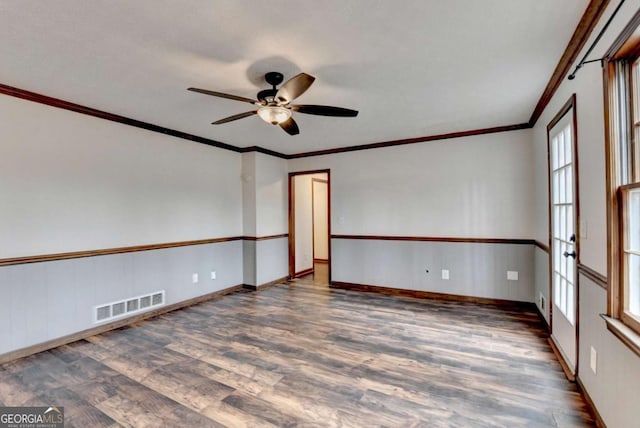 empty room featuring ceiling fan, ornamental molding, a healthy amount of sunlight, and dark hardwood / wood-style floors