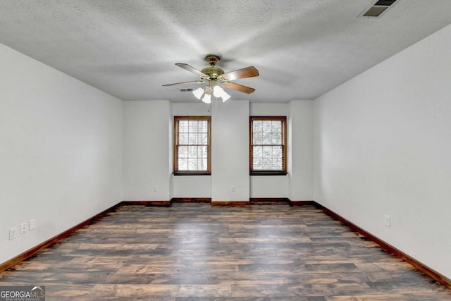 empty room featuring dark wood-type flooring, ceiling fan, and a textured ceiling