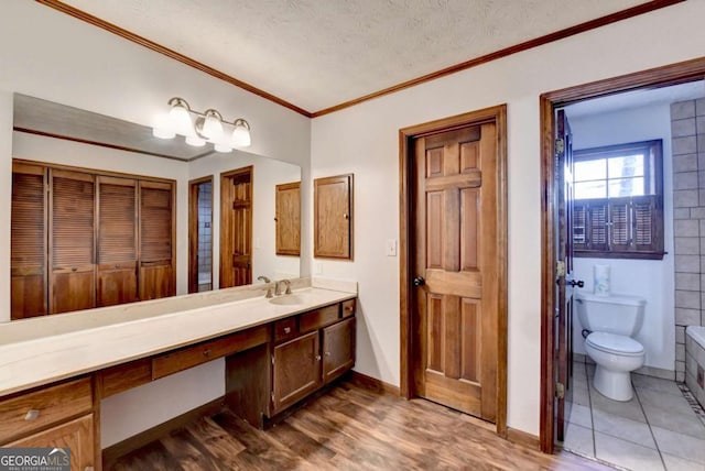 bathroom with hardwood / wood-style flooring, vanity, ornamental molding, toilet, and a textured ceiling