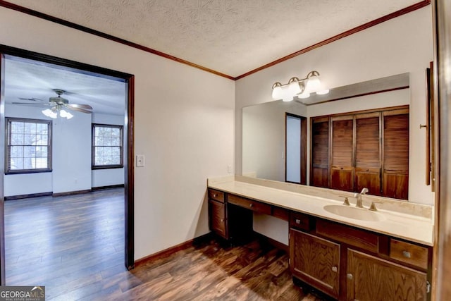 bathroom featuring crown molding, ceiling fan, vanity, wood-type flooring, and a textured ceiling