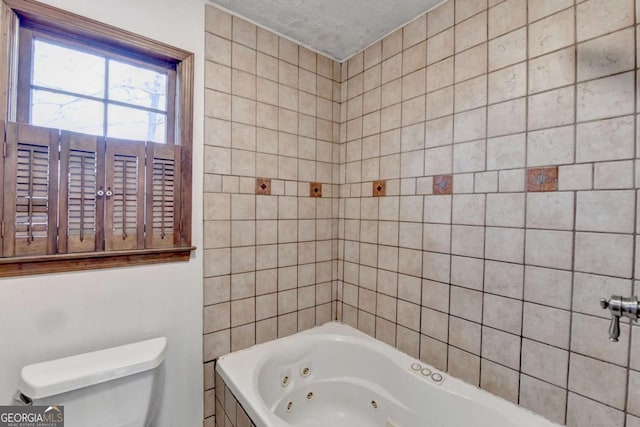 bathroom with a tub to relax in, a textured ceiling, and toilet