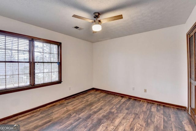 spare room with dark wood-type flooring, a textured ceiling, and ceiling fan