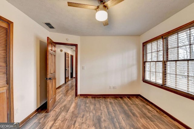 empty room with ceiling fan, a textured ceiling, and dark hardwood / wood-style flooring