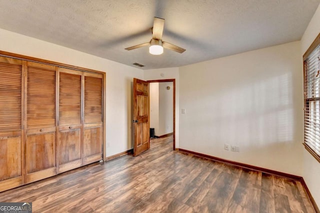 unfurnished bedroom featuring a closet, dark hardwood / wood-style floors, a textured ceiling, and ceiling fan