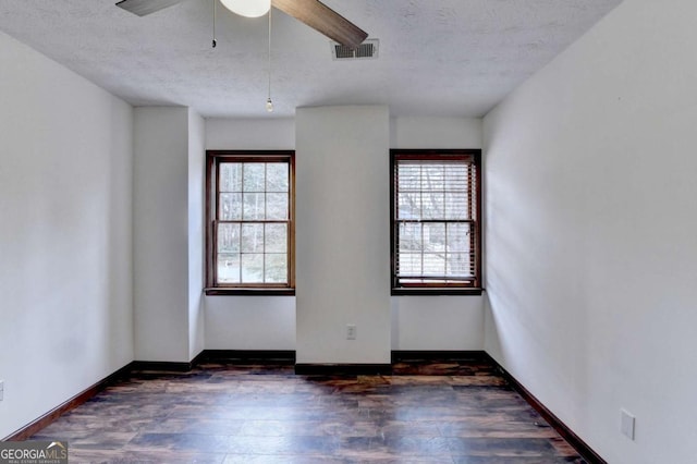 empty room with dark hardwood / wood-style flooring, ceiling fan, a wealth of natural light, and a textured ceiling