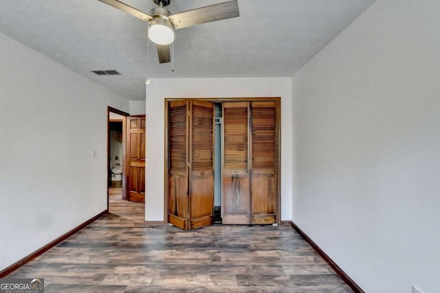 unfurnished bedroom featuring dark hardwood / wood-style flooring, a closet, and ceiling fan