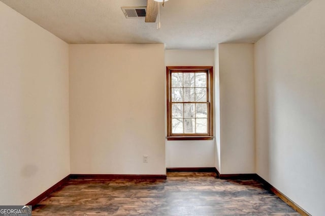 spare room with ceiling fan, dark hardwood / wood-style floors, and a textured ceiling