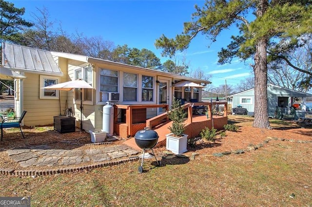 rear view of house with a wooden deck, a sunroom, and a lawn