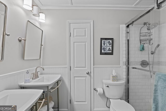 bathroom with crown molding, a shower with shower door, and toilet