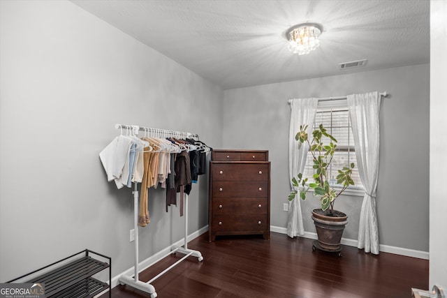 spacious closet featuring an inviting chandelier and dark hardwood / wood-style floors