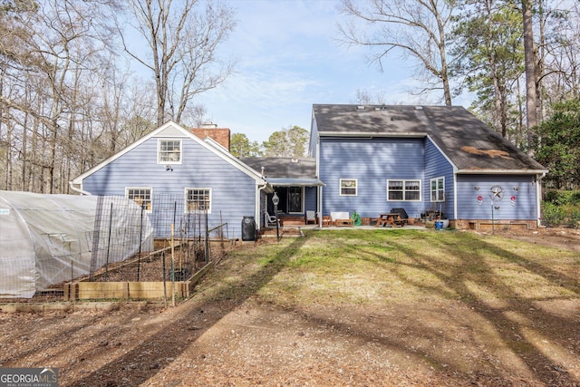 back of house with an outdoor structure and a lawn