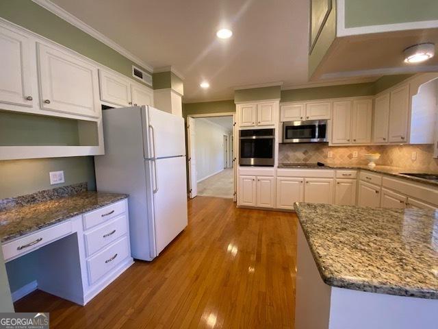 kitchen with white cabinetry, backsplash, dark stone countertops, and appliances with stainless steel finishes