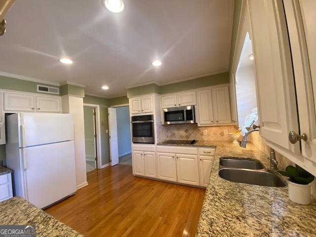 kitchen featuring light stone counters, appliances with stainless steel finishes, sink, and white cabinets