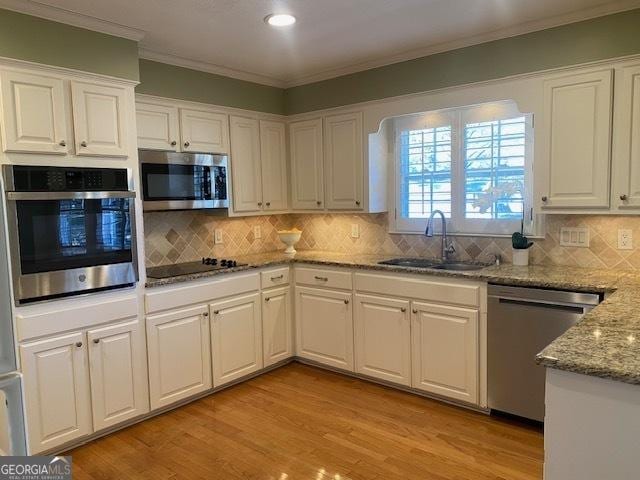 kitchen with white cabinetry, appliances with stainless steel finishes, sink, and light stone counters