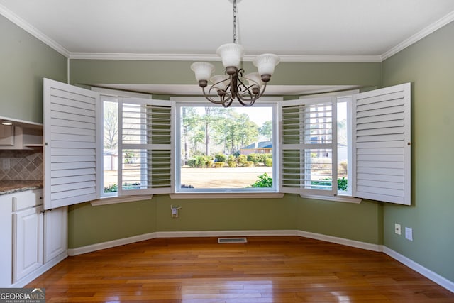 unfurnished dining area with crown molding, plenty of natural light, a chandelier, and light hardwood / wood-style floors