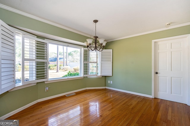 unfurnished room with a notable chandelier, ornamental molding, and hardwood / wood-style floors