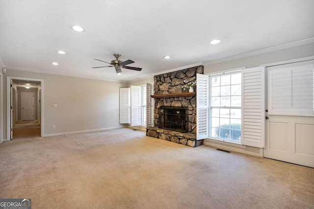 unfurnished living room featuring crown molding, a stone fireplace, light carpet, and ceiling fan