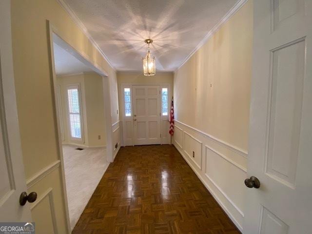 doorway to outside featuring ornamental molding and dark parquet floors