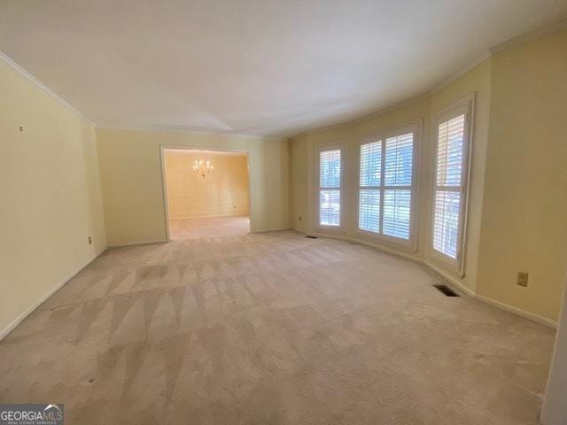 empty room with ornamental molding, light carpet, and a notable chandelier