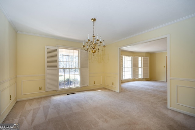 empty room with crown molding, light colored carpet, a healthy amount of sunlight, and an inviting chandelier