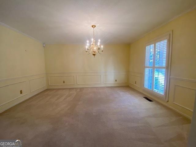 carpeted spare room featuring a notable chandelier and crown molding