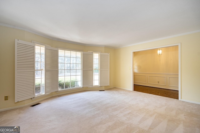 spare room featuring crown molding and light colored carpet