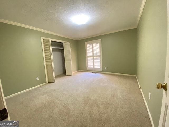 unfurnished bedroom featuring light carpet, ornamental molding, a closet, and a textured ceiling