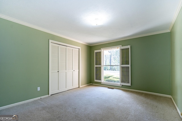 unfurnished bedroom with crown molding, a closet, a textured ceiling, and carpet