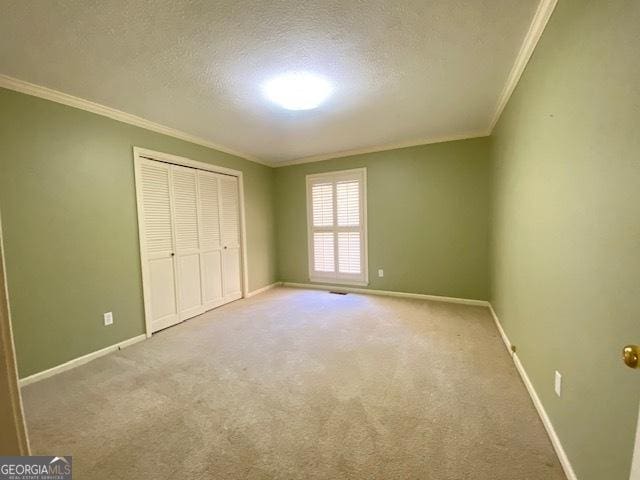 unfurnished bedroom featuring carpet floors, ornamental molding, a closet, and a textured ceiling