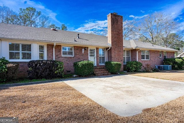 ranch-style home with a front lawn and central air condition unit