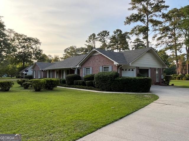 ranch-style house with a garage and a lawn