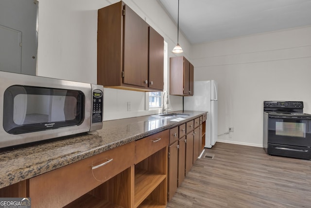 kitchen with sink, hanging light fixtures, white refrigerator, light hardwood / wood-style floors, and black / electric stove