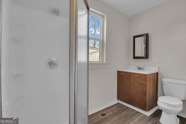 bathroom with wood-type flooring, toilet, a shower with door, and vanity